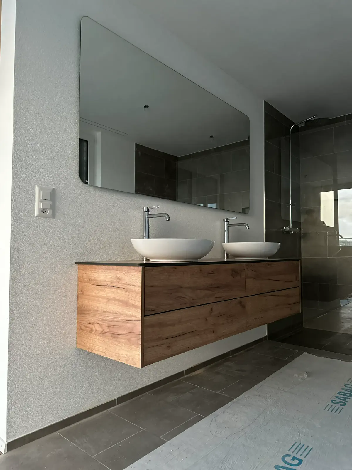Moderner Doppelwaschplatz mit zwei Aufsatzwaschbecken, wandhängendem Holz-Unterschrank und großem Spiegel