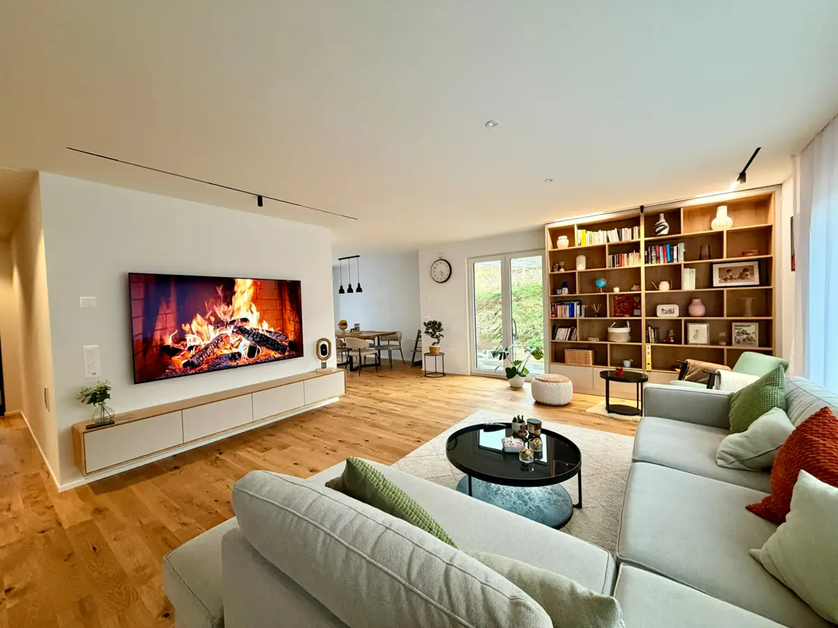 Helles Wohnzimmer mit moderner TV-Kommode, großem Wandregal aus Holz und minimalistischer Einrichtung